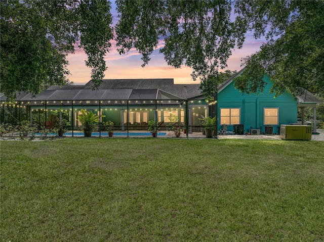 7427 20th St, Zephyrhills, FL 33540 - back of property at dusk featuring a yard, an outdoor pool, and glass enclosure