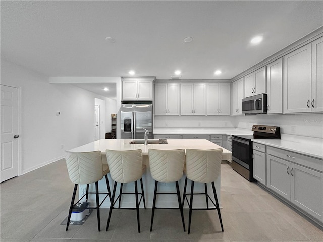 5336 Patano Loop, Palmetto, FL 34221 - kitchen featuring stainless steel appliances, gray cabinets, a kitchen island with sink, a breakfast bar, and recessed lighting