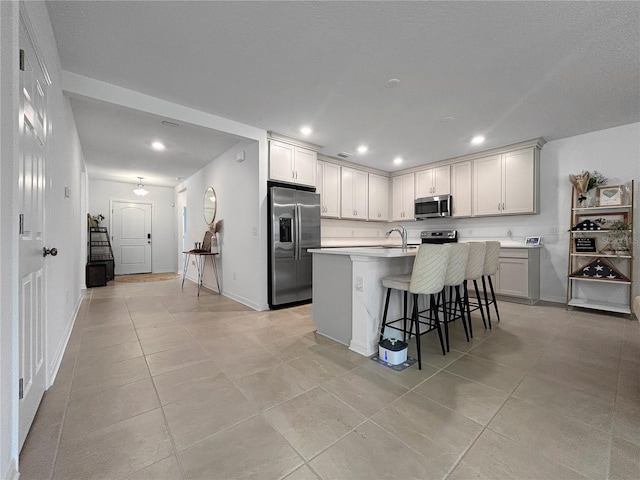 5336 Patano Loop, Palmetto, FL 34221 - kitchen featuring appliances with stainless steel finishes, light tile patterned floors, a kitchen island with sink, a breakfast bar area, and recessed lighting