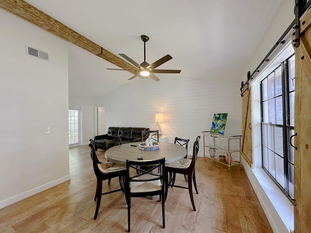 1548 Foxboro Dr, Palm Harbor, FL 34683 - dining room featuring a barn door, vaulted ceiling, light wood-style flooring, and a ceiling fan