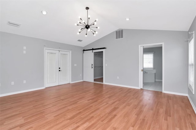 4317 S Hale Ave, Tampa, FL 33611 - unfurnished living room featuring a chandelier, vaulted ceiling, a barn door, and light wood-type flooring