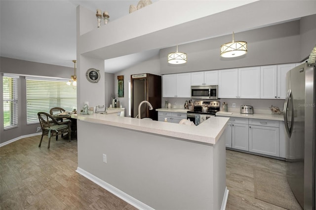 1115 Ashbourne Cir, Trinity, FL 34655 - kitchen featuring stainless steel appliances, light wood finished floors, white cabinetry, light countertops, and a peninsula