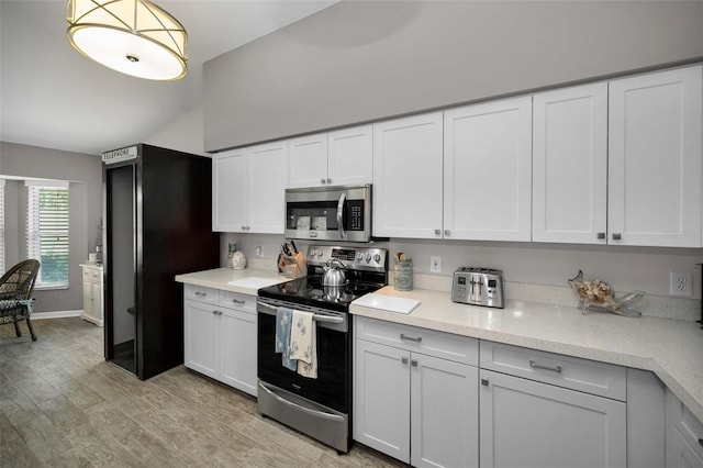 1115 Ashbourne Cir, Trinity, FL 34655 - kitchen featuring stainless steel appliances, white cabinets, and light wood-type flooring