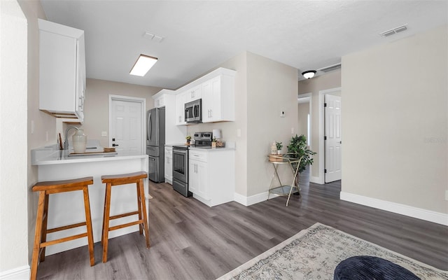 3907 W Walnut St, Tampa, FL 33607 - kitchen featuring stainless steel appliances, dark wood finished floors, light countertops, and white cabinets
