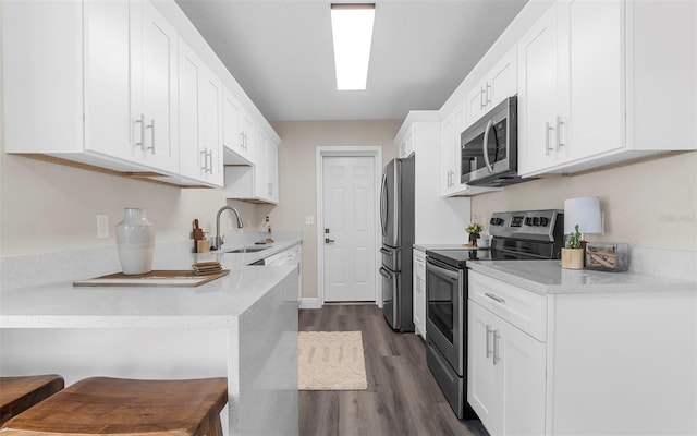 3907 W Walnut St, Tampa, FL 33607 - kitchen featuring stainless steel appliances, dark wood-style floors, white cabinetry, and a kitchen breakfast bar