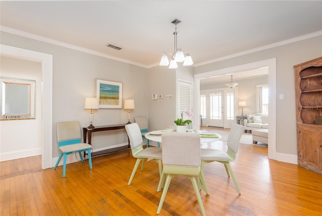 3611 W Bay To Bay Blvd, Tampa, FL 33611 - dining space featuring light wood-type flooring, crown molding, and a chandelier