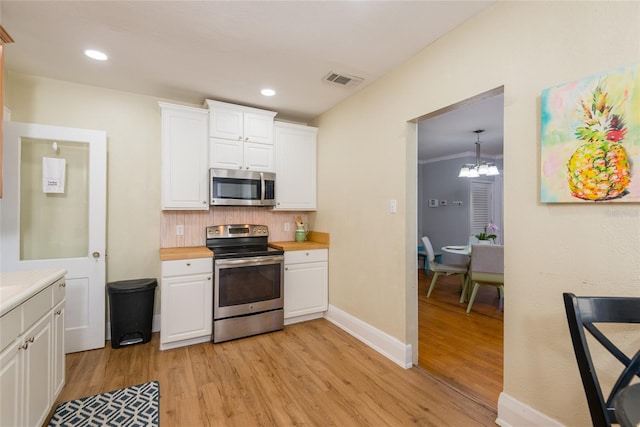 3611 W Bay To Bay Blvd, Tampa, FL 33611 - kitchen with stainless steel appliances, light wood finished floors, white cabinetry, backsplash, and recessed lighting