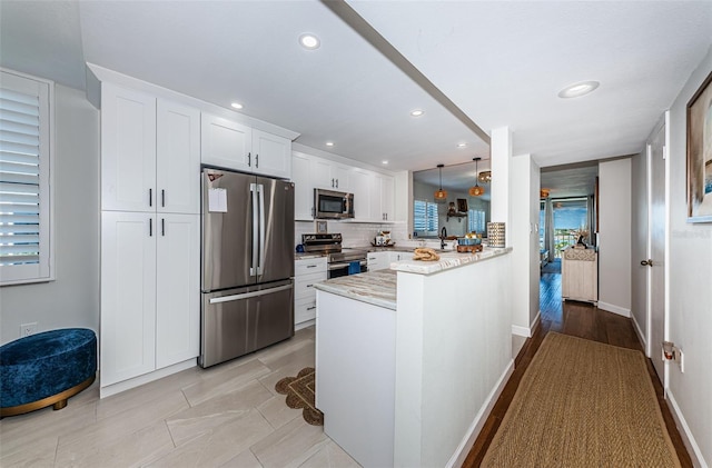 1324 Pasadena Ave S Unit 501, South Pasadena, FL 33707 - kitchen with stainless steel appliances, white cabinetry, a peninsula, recessed lighting, and decorative backsplash