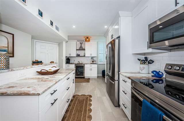 1324 Pasadena Ave S Unit 501, South Pasadena, FL 33707 - kitchen with appliances with stainless steel finishes, wine cooler, decorative backsplash, white cabinetry, and open shelves