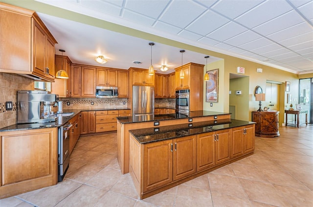 1324 Pasadena Ave S Unit 501, South Pasadena, FL 33707 - kitchen with appliances with stainless steel finishes, light tile patterned floors, brown cabinets, tasteful backsplash, and dark stone countertops