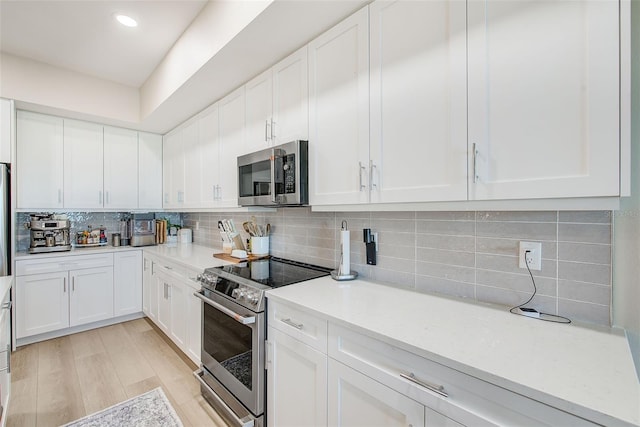 400 150th Ave Unit 504, Madeira Beach, FL 33708 - kitchen with stainless steel appliances, light countertops, backsplash, white cabinetry, and recessed lighting
