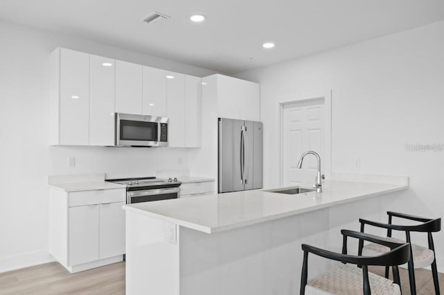 400 150th Ave Unit 504, Madeira Beach, FL 33708 - kitchen featuring stainless steel appliances, a kitchen breakfast bar, light wood-type flooring, white cabinets, and light countertops