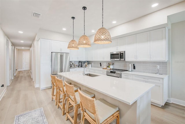 400 150th Ave Unit 504, Madeira Beach, FL 33708 - kitchen featuring stainless steel appliances, a breakfast bar area, light wood-style floors, backsplash, and light countertops