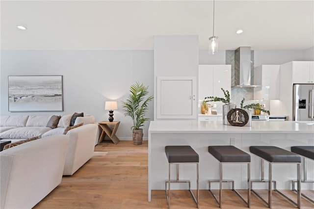 532 W Plaza Pl Unit 3, Tampa, FL 33602 - kitchen with stainless steel fridge, wall chimney range hood, a kitchen bar, white cabinets, and light countertops