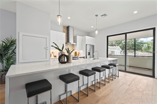 532 W Plaza Pl Unit 3, Tampa, FL 33602 - kitchen featuring wall chimney exhaust hood, stainless steel fridge, white cabinetry, light countertops, and recessed lighting