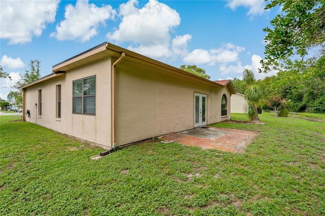 8671 Cypress Lakes Blvd, New Port Richey, FL 34653 - view of side of home featuring stucco siding, french doors, a yard, and a patio