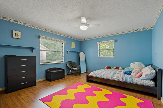 8671 Cypress Lakes Blvd, New Port Richey, FL 34653 - bedroom with multiple windows, wood finished floors, a textured ceiling, and a ceiling fan