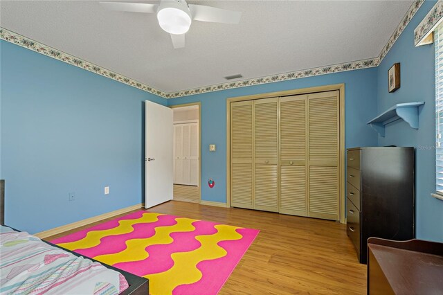 8671 Cypress Lakes Blvd, New Port Richey, FL 34653 - bedroom with wood finished floors, a closet, a textured ceiling, and a ceiling fan