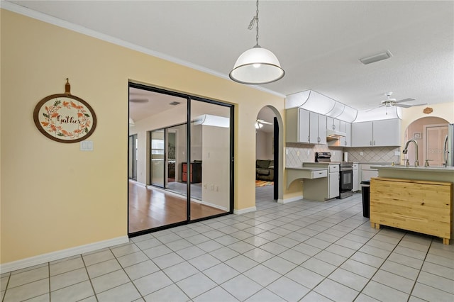8671 Cypress Lakes Blvd, New Port Richey, FL 34653 - kitchen with arched walkways, stainless steel range with electric cooktop, tasteful backsplash, crown molding, and light countertops