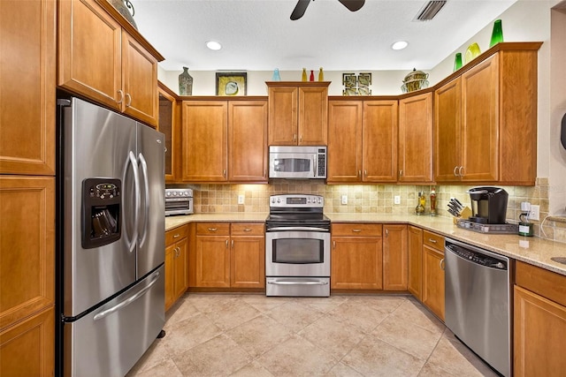 15744 Crystal Waters Dr, Wimauma, FL 33598 - kitchen featuring appliances with stainless steel finishes, brown cabinetry, tasteful backsplash, and a ceiling fan