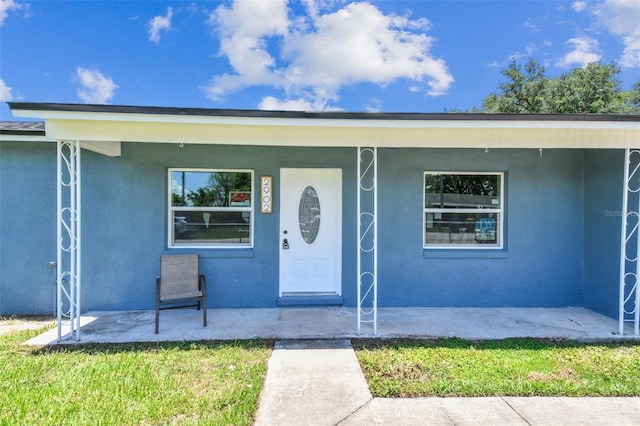 2902 Wheeler St, Bartow, FL 33830 - view of exterior entry featuring stucco siding, a porch, and a yard