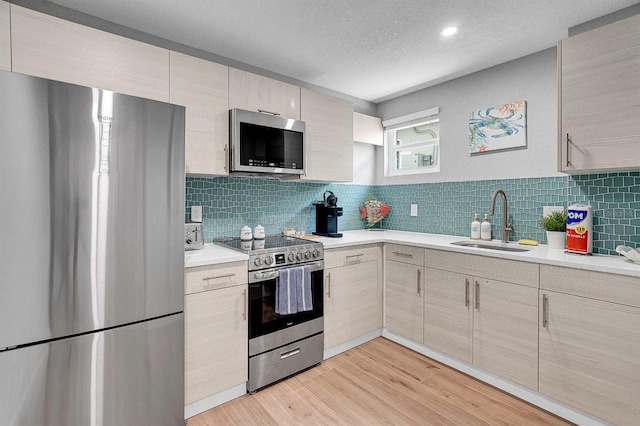 122 Coral Ave, Redington Shores, FL 33708 - kitchen with stainless steel appliances, light countertops, light wood-type flooring, tasteful backsplash, and a textured ceiling