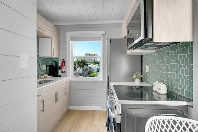 122 Coral Ave, Redington Shores, FL 33708 - kitchen featuring light wood-style flooring, tasteful backsplash, appliances with stainless steel finishes, and light countertops