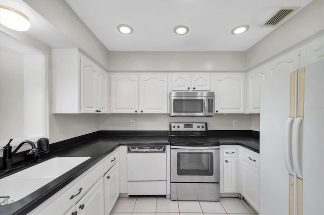 8451 Candlewood Rd Unit 8451, Seminole, FL 33777 - kitchen featuring appliances with stainless steel finishes, dark countertops, white cabinets, light tile patterned floors, and recessed lighting