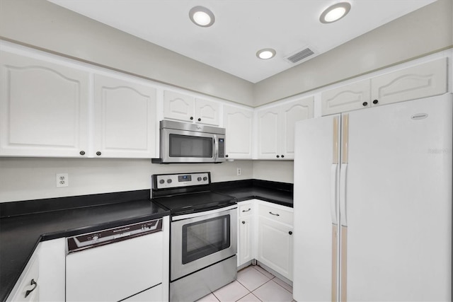 8451 Candlewood Rd Unit 8451, Seminole, FL 33777 - kitchen featuring stainless steel appliances, dark countertops, white cabinets, light tile patterned flooring, and recessed lighting