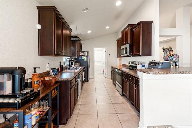 10909 Kirkwall Port Dr, Wimauma, FL 33598 - kitchen with appliances with stainless steel finishes, dark countertops, dark brown cabinetry, lofted ceiling, and light tile patterned floors