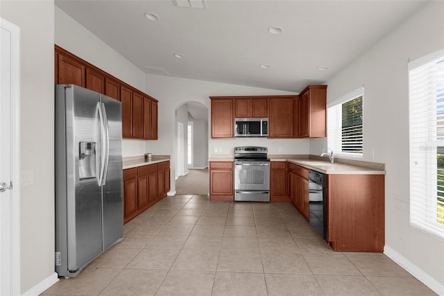 1280 Hill Flower Dr, Brooksville, FL 34604 - kitchen featuring appliances with stainless steel finishes, arched walkways, lofted ceiling, light countertops, and light tile patterned floors