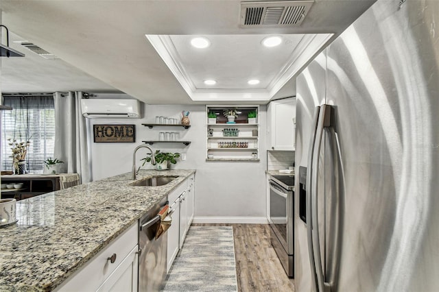 5744 Thrush Dr, New Port Richey, FL 34652 - kitchen featuring stainless steel appliances, a tray ceiling, an AC wall unit, white cabinetry, and light wood-style floors