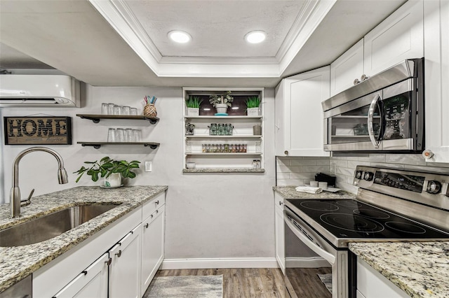 5744 Thrush Dr, New Port Richey, FL 34652 - kitchen with stainless steel appliances, a raised ceiling, an AC wall unit, light wood-style flooring, and ornamental molding
