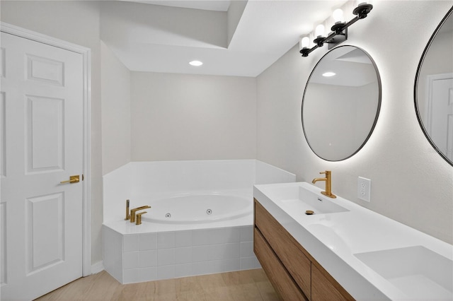 5430 Eagles Point Cir Unit 202, Sarasota, FL 34231 - bathroom featuring double vanity, a whirlpool tub, wood finished floors, and recessed lighting