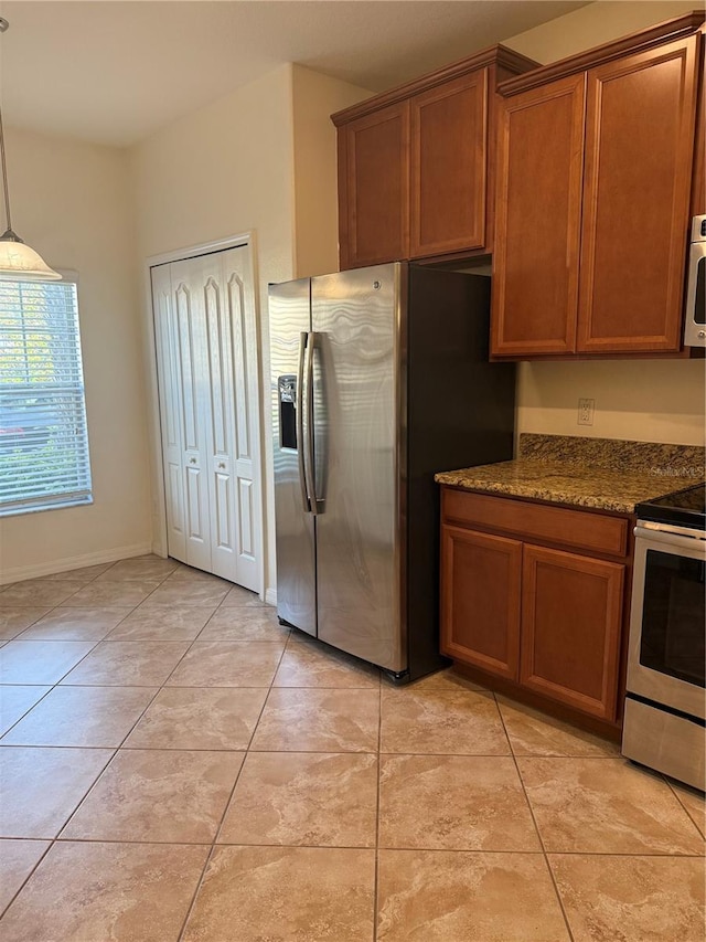 2411 Willimette Dr, Wesley Chapel, FL 33543 - kitchen featuring stainless steel appliances, brown cabinets, light tile patterned floors, dark stone counters, and pendant lighting