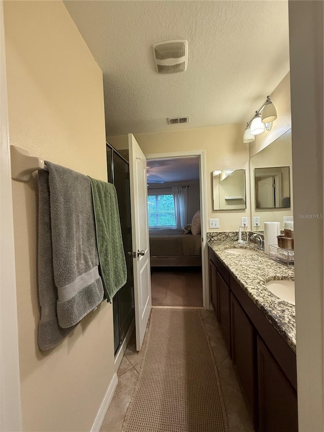 2411 Willimette Dr, Wesley Chapel, FL 33543 - bathroom featuring connected bathroom, double vanity, a textured ceiling, a stall shower, and tile patterned floors
