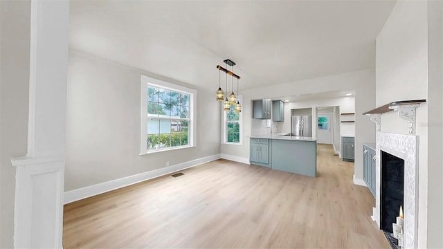 1005 45th St W, Bradenton, FL 34209 - kitchen featuring freestanding refrigerator, light wood-type flooring, light countertops, a fireplace, and gray cabinetry