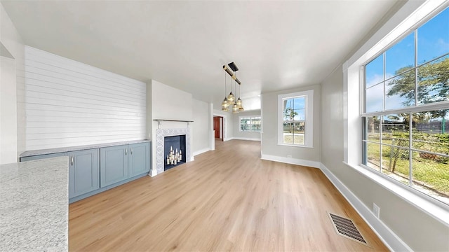 1005 45th St W, Bradenton, FL 34209 - unfurnished living room with light wood-style flooring, a fireplace, and a chandelier