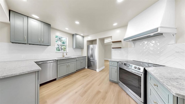 1005 45th St W, Bradenton, FL 34209 - kitchen featuring stainless steel appliances, gray cabinetry, custom range hood, open shelves, and light wood-style flooring