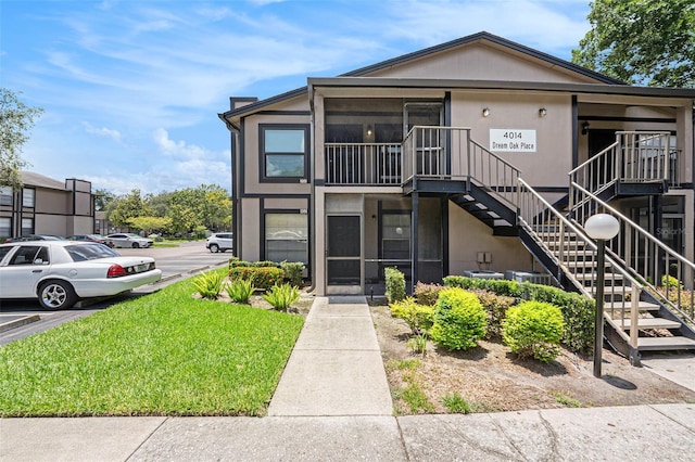 4014 Dream Oak Pl Unit 202, Tampa, FL 33613 - view of front of property featuring stairs, uncovered parking, a front lawn, and stucco siding