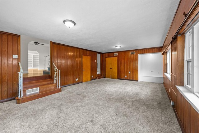 2819 N Central Ave, Tampa, FL 33602 - carpeted empty room with wood walls, stairway, and a ceiling fan