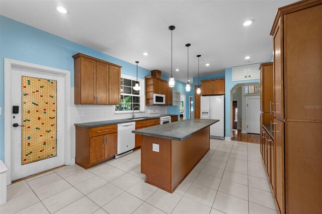 2819 N Central Ave, Tampa, FL 33602 - kitchen with white appliances, dark countertops, brown cabinetry, a center island, and decorative light fixtures