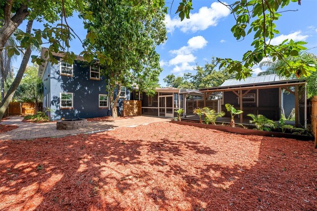 2819 N Central Ave, Tampa, FL 33602 - rear view of property with a sunroom, an outdoor fire pit, stucco siding, a vegetable garden, and a patio area