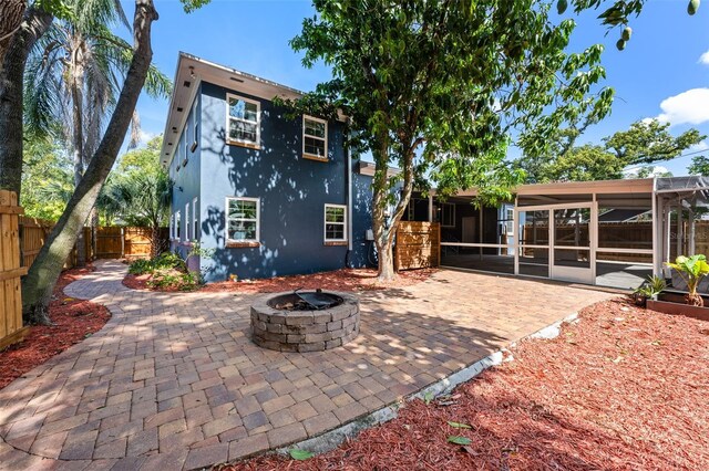 2819 N Central Ave, Tampa, FL 33602 - back of house featuring a sunroom, a patio area, stucco siding, a fire pit, and a fenced backyard