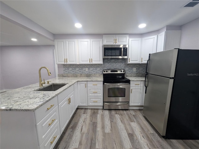 1028 E 93rd Ave Unit A, Tampa, FL 33612 - kitchen with appliances with stainless steel finishes, light wood finished floors, white cabinetry, a peninsula, and recessed lighting