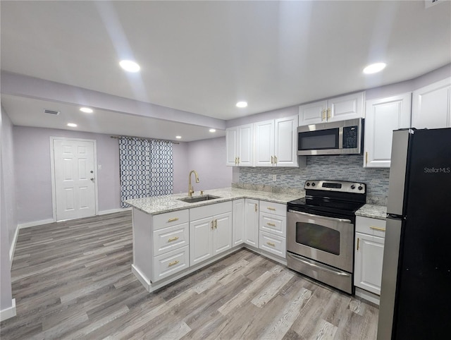 1028 E 93rd Ave Unit A, Tampa, FL 33612 - kitchen featuring stainless steel appliances, a peninsula, light wood-type flooring, white cabinetry, and recessed lighting