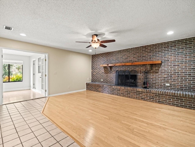 1015 Hastings Ct, Lutz, FL 33548 - unfurnished living room with a ceiling fan, brick wall, light tile patterned floors, a textured ceiling, and a brick fireplace