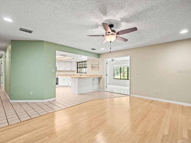 1015 Hastings Ct, Lutz, FL 33548 - unfurnished living room with a ceiling fan, light wood-type flooring, recessed lighting, and a textured ceiling