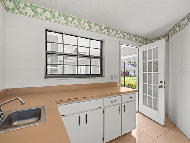 1015 Hastings Ct, Lutz, FL 33548 - kitchen with a textured ceiling, white cabinets, light tile patterned floors, light countertops, and wallpapered walls