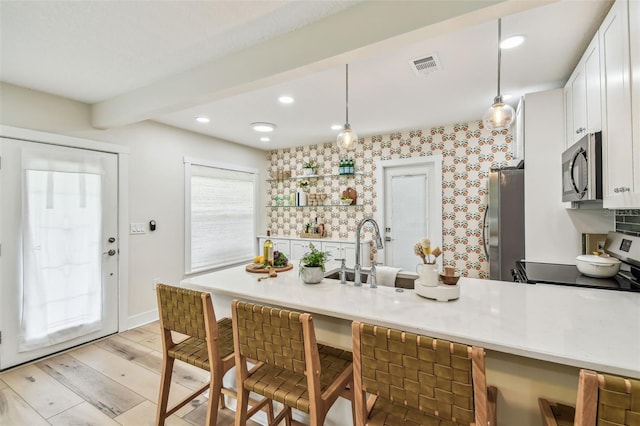 2452 Bayshore Blvd, Dunedin, FL 34698 - kitchen with stainless steel appliances, a kitchen breakfast bar, white cabinetry, a peninsula, and light countertops